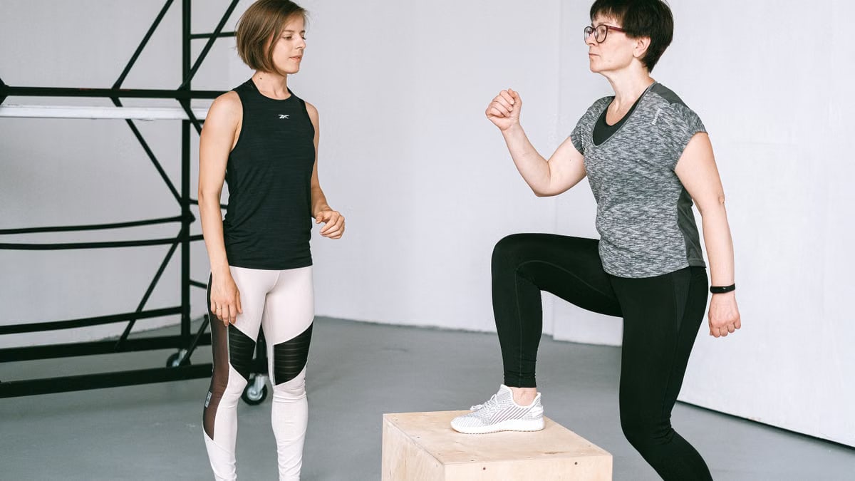 Fitness coach guides a woman in workout indoors. Focus on exercise and healthy lifestyle.